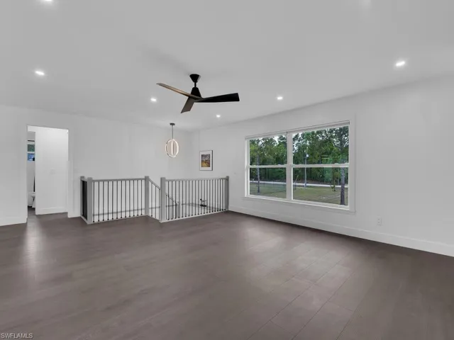 Unfurnished living room featuring dark wood-type flooring and ceiling fan