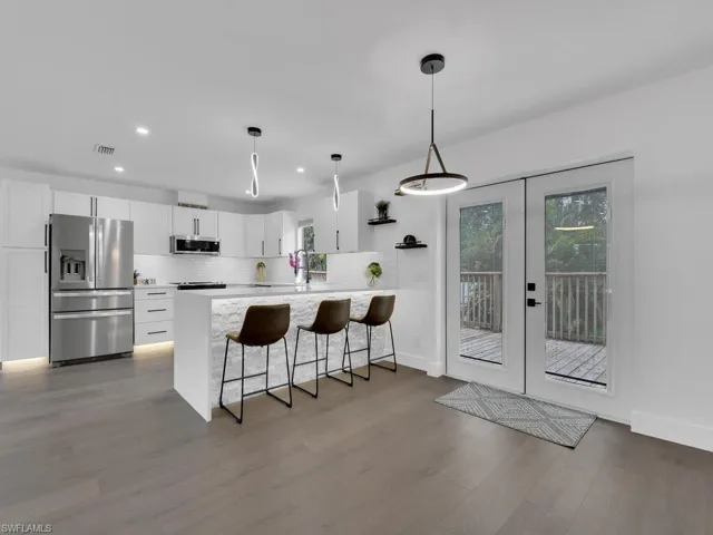 Kitchen featuring kitchen peninsula, stainless steel appliances, backsplash, hardwood / wood-style flooring, and white cabinetry