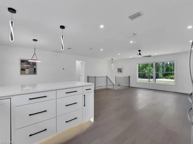 Kitchen with ceiling fan, decorative light fixtures, white cabinets, and hardwood / wood-style flooring
