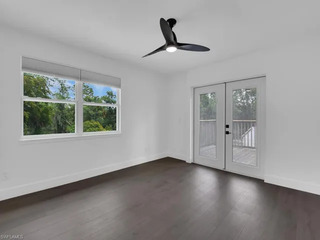 Empty room featuring a wealth of natural light, ceiling fan, french doors, and dark hardwood / wood-style floors