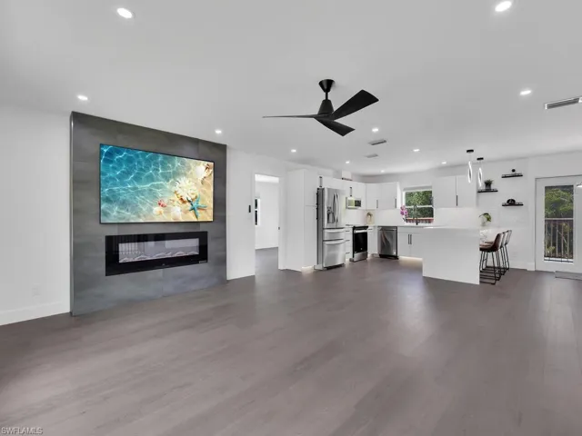 Unfurnished living room featuring ceiling fan, dark hardwood / wood-style flooring, and a fireplace