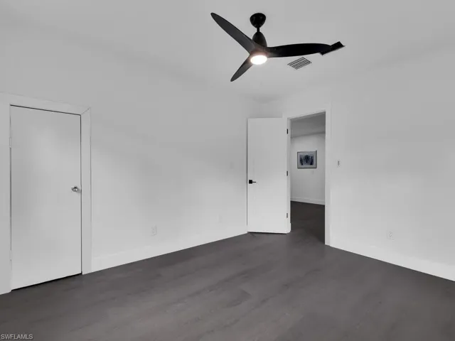 Unfurnished room with ceiling fan and dark wood-type flooring