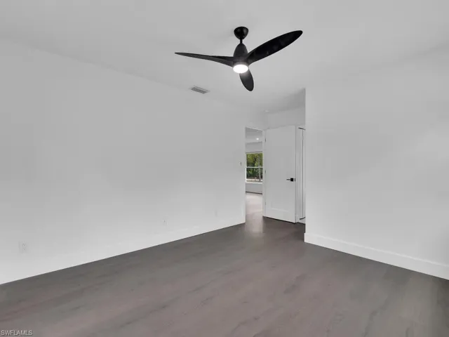 Spare room with dark wood-type flooring and ceiling fan