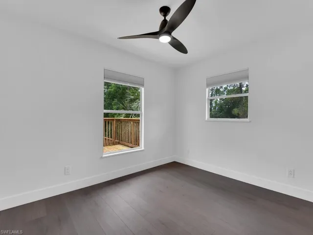 Spare room featuring dark wood-type flooring, plenty of natural light, and ceiling fan