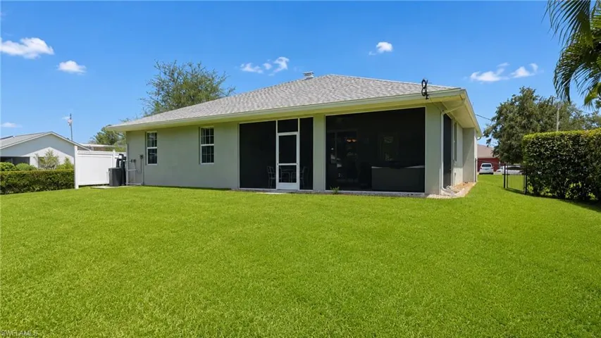 Expansive rear yard featuring a manicured lawn and a screened patio