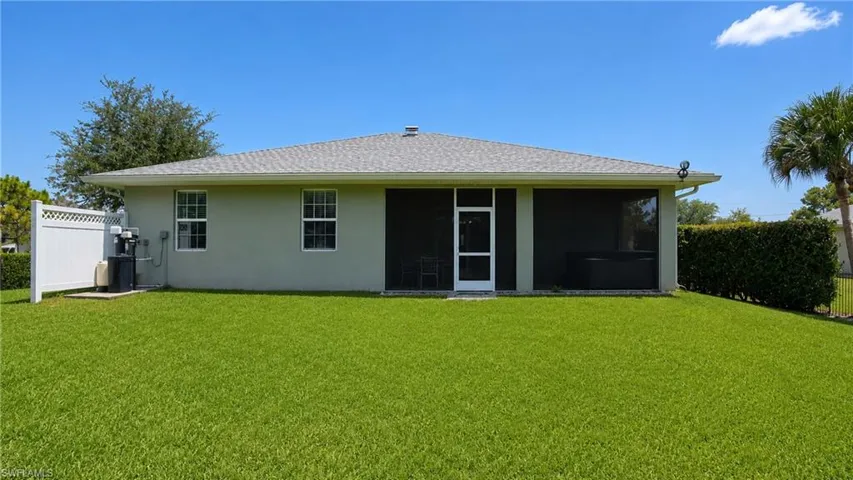Expansive backyard featuring a manicured lawn, screened-in patio, and privacy landscaping