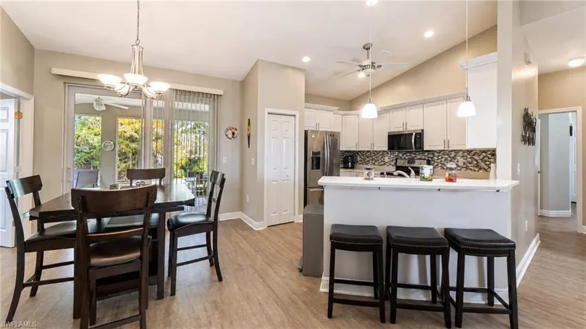 Open-concept living space featuring wood-finish flooring, vaulted ceilings, and a neutral color palette