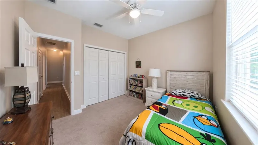 Bedroom featuring neutral wall paint, carpet flooring, a ceiling fan, a window with blinds, and bi-fold closet doors