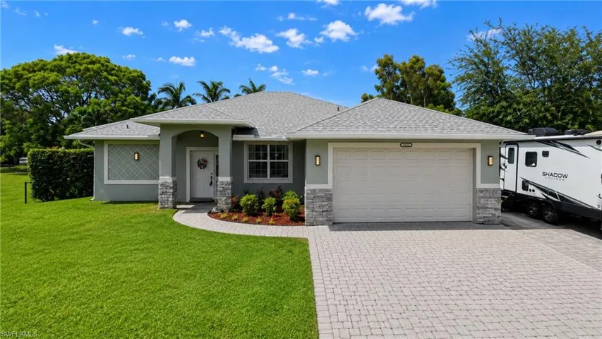 Contemporary home featuring a paver driveway, stone accents, and a covered entry