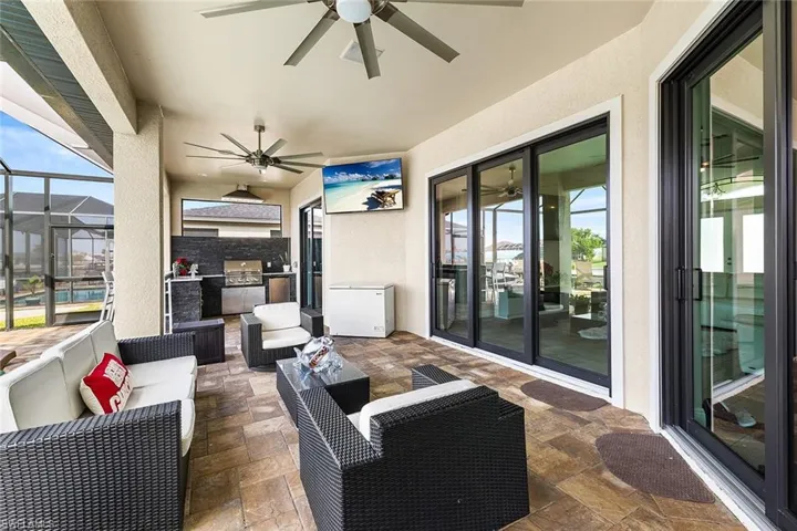 View of featuring impact sliders, outdoor lounge area, outdoor kitchen, and ceiling fan