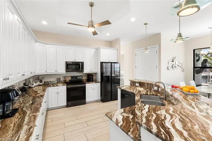 Kitchen with black appliances, white cabinets and granite countertops