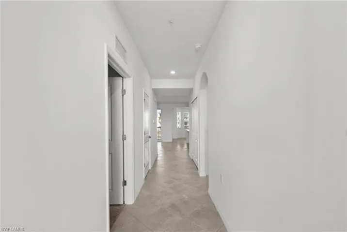 Corridor with visible vents, arched walkways, and baseboards