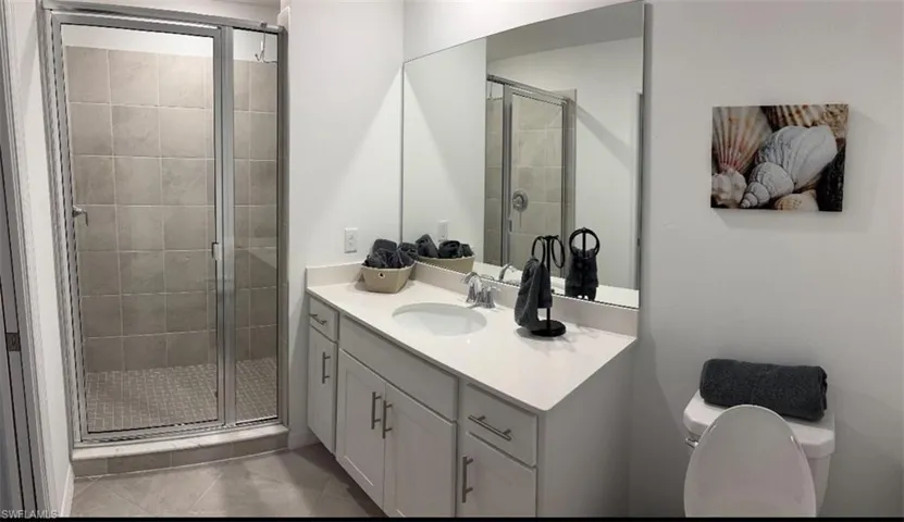 Full bath featuring a shower stall, vanity, and light tile patterned floors
