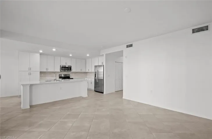 Kitchen featuring visible vents, stainless steel appliances, light countertops, and open floor plan