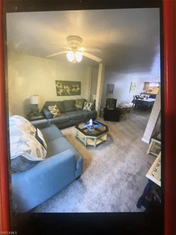 Carpeted living area featuring ceiling fan