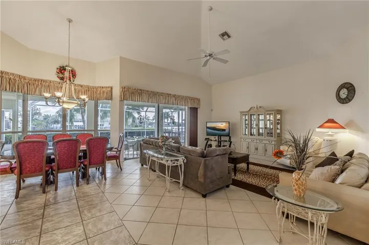 Living room featuring high vaulted ceiling, tile patterned flooring, and a chandelier