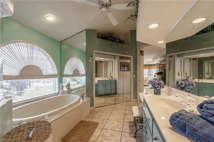 Bathroom with a garden tub, two vanities, recessed lighting, light tile patterned flooring, and ceiling fan