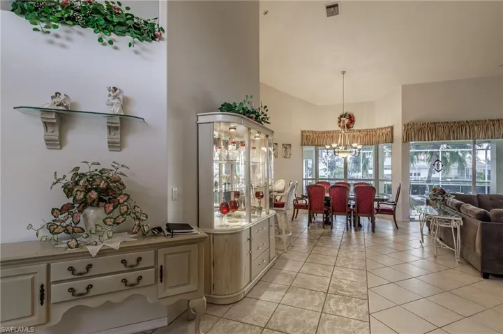 Living room featuring a chandelier, high vaulted ceiling, a ceiling fan, and light tile patterned floors