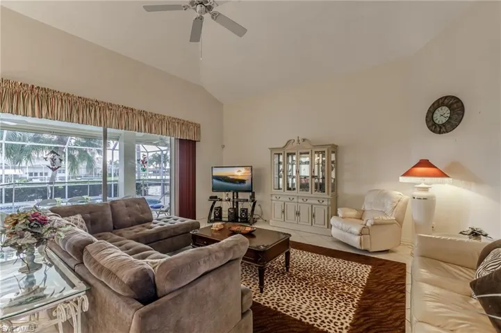 Living area featuring light tile patterned floors, high vaulted ceiling, a chandelier, and a ceiling fan