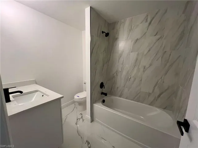 Full bathroom with toilet, tiled shower / bath, and vanity