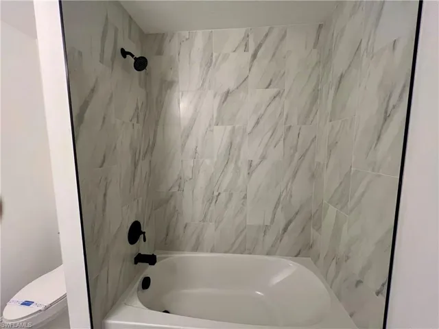 Bathroom with tiled shower / bath combo and toilet