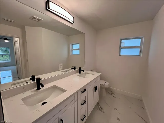 Primary bathroom with toilet and dual sinks and vanity.