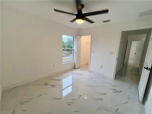 Guest bedroom with ceiling fan and walk in closet.