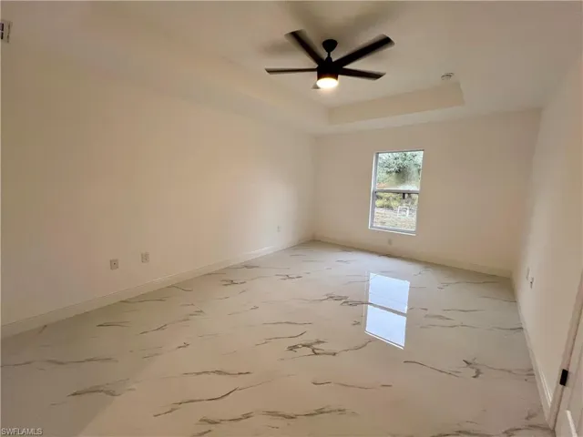 Primary bedroom with ceiling fan and a tray ceiling