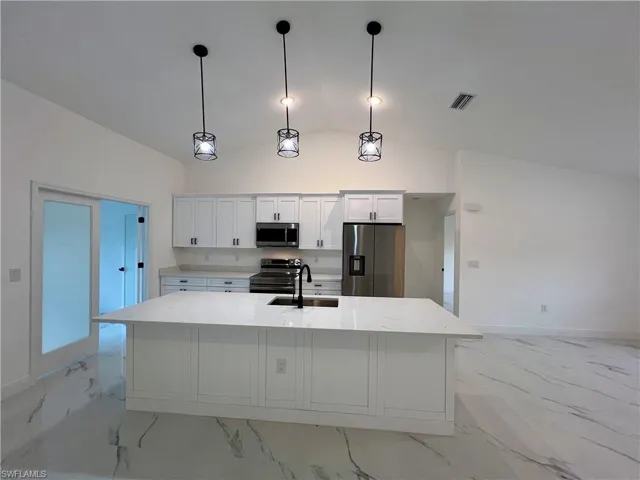 Kitchen with white cabinets, QUARTZ TOPS stainless steel appliances, hanging light fixtures, and sink
