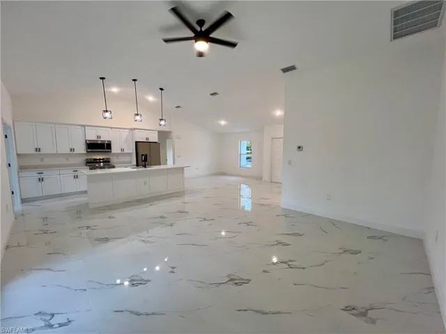 Living room with ceiling fan and high volume ceilings.
