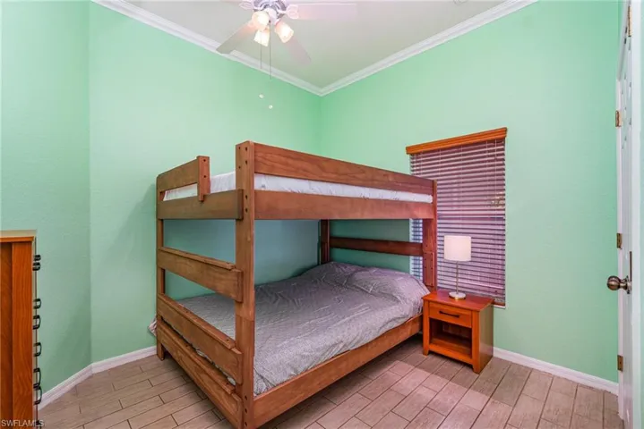 Bedroom with wood tiled floors, ceiling fan, and crown molding