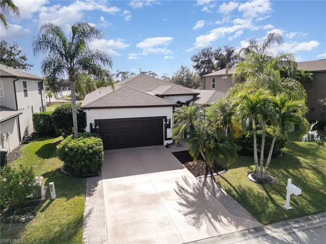 View of front of house featuring concrete driveway, a front lawn, stucco siding, and a garage