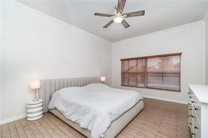Bedroom with wood finish floors, crown molding, and ceiling fan