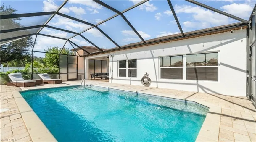 Swimming pool featuring glass enclosure, a patio area, and a sunroom