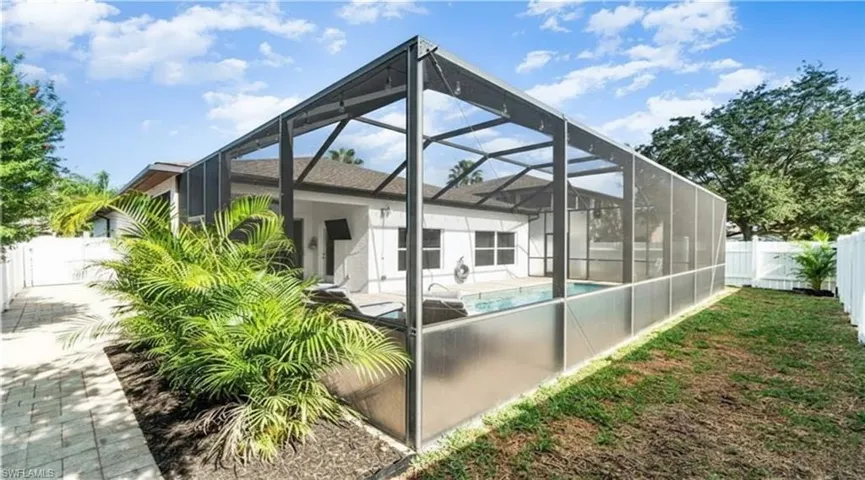 Rear view of house with a fenced backyard, glass enclosure, a sunroom, and a patio