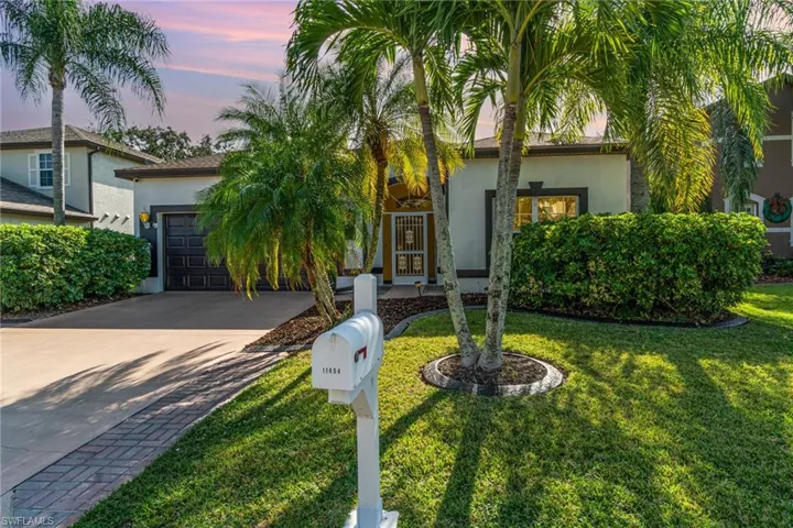 View of front of property featuring concrete driveway, stucco siding, an attached garage, and a yard