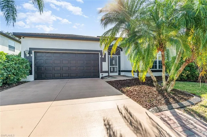 View of front of home featuring stucco siding, driveway, and a garage