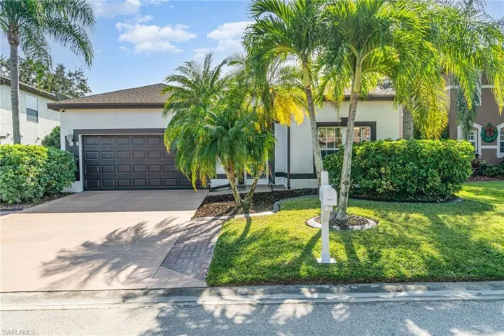View of property hidden behind natural elements with driveway, stucco siding, a front yard, and a garage