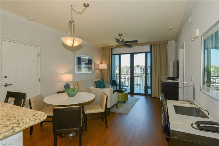 Dining area with ornamental molding, dark wood-style floors, and ceiling fan
