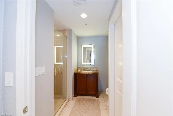 Full bath with tile patterned floors, a stall shower, toilet, vanity, and recessed lighting