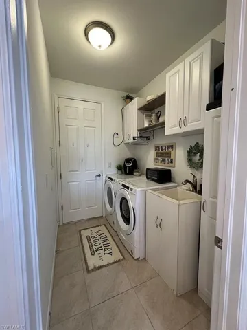 Laundry area featuring cabinet space, light tile patterned floors, and washer and dryer