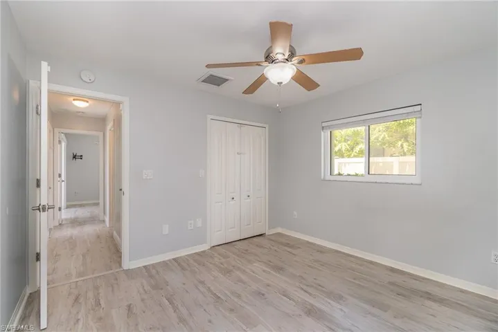 Unfurnished guest bedroom featuring a closet, ceiling fan, and light hardwood / wood-style flooring