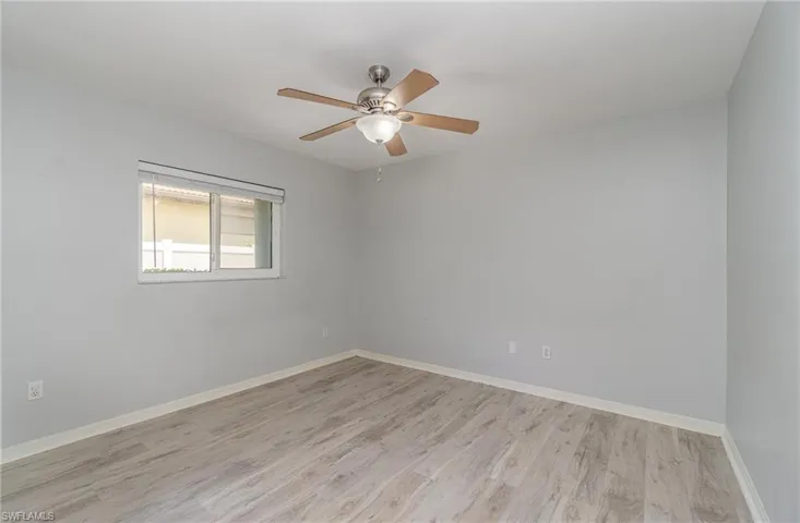 Unfurnished guest bedroom with ceiling fan and light wood-type flooring