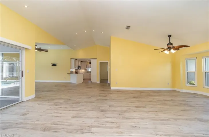 Unfurnished sitting area, dining area,  living room featuring high vaulted ceiling, ceiling fan, and light hardwood / wood-style flooring
