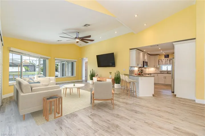 Virtually Staged Living room area featuring high vaulted ceiling, ceiling fan, and light hardwood / wood-style flooring