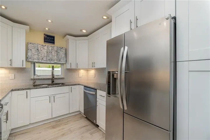 Kitchen with stainless steel appliances and finishes, double sink, tasteful backsplash, and light hardwood / wood-style flooring