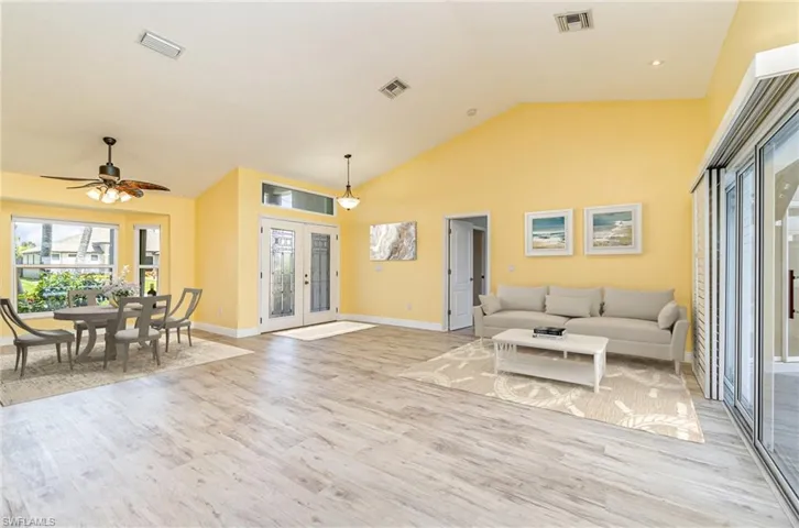 Virtually Staged sitting area and dining area with high vaulted ceiling, ceiling fan, light hardwood / wood-style floors, and French door front entry