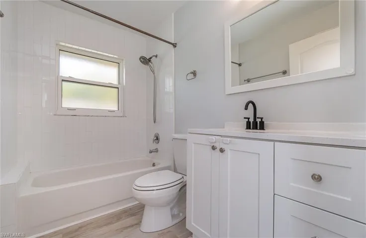 Full guest bathroom featuring hardwood / wood-style floors, vanity, toilet, and tiled shower / bath combo