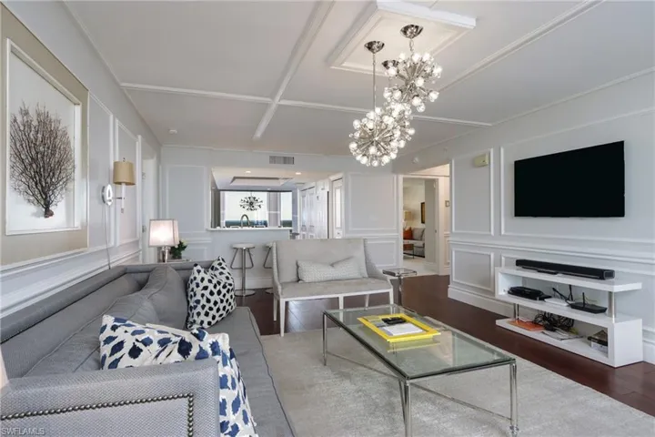 Living room featuring coffered ceiling, hardwood / wood-style flooring, and an inviting chandelier