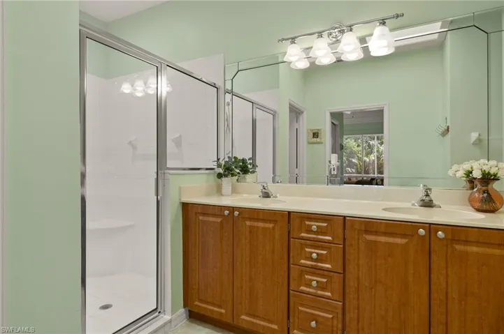Bathroom with a sink, a stall shower, and double vanity